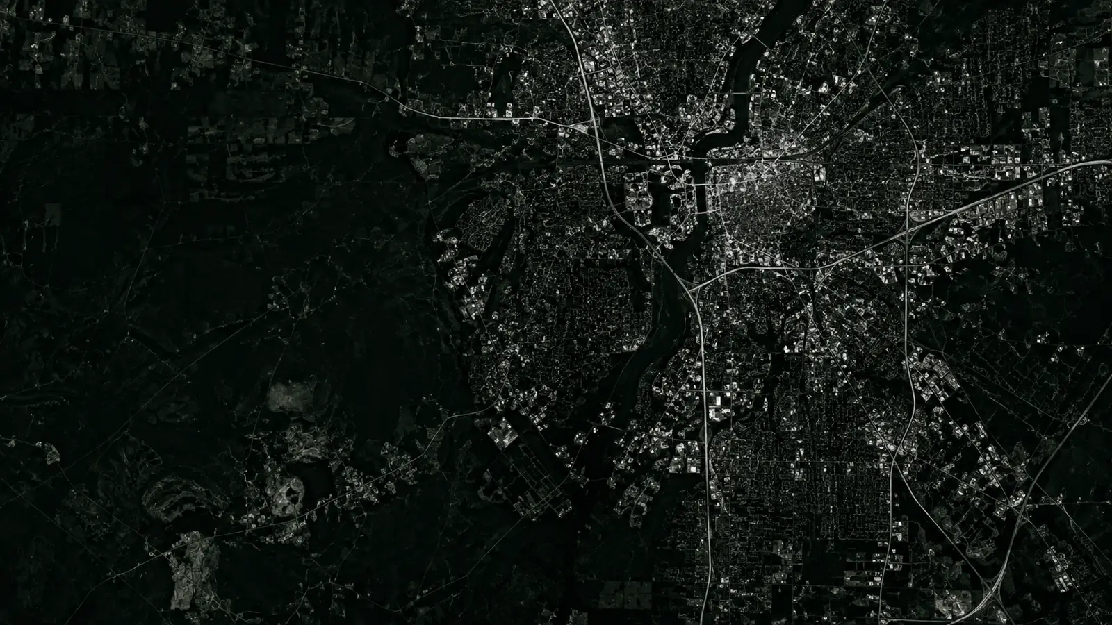High-contrast aerial night map of a district with illuminated roads